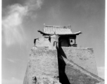 A structure in northern China, elevated on a brick tower set upon the remnants of a town wall. During WWII. This is almost certainly a temple.