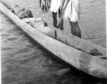 Two men near Misamari, India, show off a tidy string of fish as they stand next to their very long canoe.   Image provided by  "P. Noel."   In the CBI during WWII.