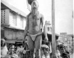 An Indian fakir and interested crowd look at cameraman during WWII.