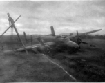 A B-25 in the ditch next to a runway or taxiway at an American base in China, during WWII. Crews work to salvage the aircraft using a simple human-powered tripod crane.