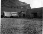 "The Latest In Shops And Equipment--This a picture looking into a revetment that served as our work area and engineering area at Luichow [Liuzhou], China. Lt. Sohl's office was in the little shack at the right and all our tools and equipment was in the tent. We changed a lot of B-24 engines in this revetment along with replacing blown out tires and doing sheet metal repair work. We worked here until the Japanese forced us to evacuate the base and return to Luliang."