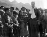 An American flyer--piece of silk parachute slung around his neck--is surrounded by appreciative crowd of Chinese people in Guangxi, China. During WWII.