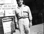 A GI stands before signs on a base in China during WWII.