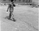 A Chinese staff person walks across an open area of a hostel in Yunnan province, China, most likely around the Luliang air base area.