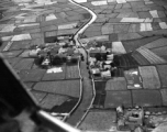 A tidy village near Kunming, as seen from the air, during WWII, with a canal passing through the village.