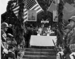 Burma Road dedication ceremony in Kunming, China, on February 4, 1945, during WWII. Review of first convoy (or one of the first convoys) to reach China. General view of the stage and reviewing party, with American and Chinese dignitaries, soldiers, and civilian VIPs. An American band plays, and an honor lines on both sides of the center carpet stand in formation.  Official dignitaries at the ceremony included, on the Chinese side, such figures as General Lung Yun, Governor of Yunnan Province,  Gen. Wang Yu-