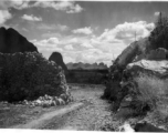 Karst mountains in the distance seen through an opening in a wall of stacked limestone. In Liuzhou, Guangxi, during WWII.