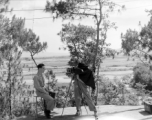 A photographer takes a portrait photo of an American serviceman. Yangkai valley in the background. During WWII in SW China. 