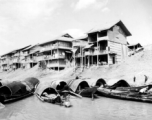 Waterside houses in China, with boats floating in the foreground, during WWII.