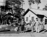 GI explorations of the hostel area at Yangkai air base during WWII: Men haul water in barrels on shoulder poles for use in the hostels.