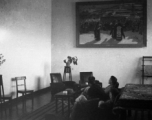 GIs rest in a nice room, under a large portrait of a Tibetan pilgrimage to a Tibetan Buddhist temple.  Probably in Lanzhou or nearby. During WWII.