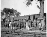 GIs and local vendor mingle during a rest stop on the train in India during WWII.