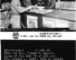 Pre-Christmas scene at the SOS (Service of Supply) PX at APO 627. Cpl Harold L. Graff, Cpl. Ben L. Rohleder, 1st Lt. Frances J. Vesset, and Anna Wong.  December 15, 1944.  Photo by Pfc. Thomas F. Melvin.  Passed by censor Emanuel Goldberg.