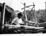 Local people in Burma near the 797th Engineer Forestry Company--A woman weaves on a loom in Burma.  During WWII.