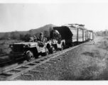 Two jeeps, fitted with steel wheels that fit the rail tracks, pull cars loaded with oil pipes. In Burma.  During WWII.  797th Engineer Forestry Company.