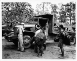 Local men observe as a GI repairs a truck in Burma.  During WWII.  797th Engineer Forestry Company.