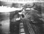 "It won't be long now! Watch bombs in air..."  This train was wiped out with low level bombs & gunfire. Note on back of the photo reads: Three track RR sliding with 17 cars and locomotive, which is destroyed, note wreckage from bomb bursts and quantity of escaping steam. 3 cars probably destroyed, more damaged. Two of track torn up by bomb bursts, hole from strafing is visible on extreme left track.  This should be Van Trai Station, French Indochina.