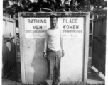 Irwin Schneckloth of 2005th Ordnance Maintenance Company, 28th Air Depot Group, poses with curiosity in front of public shower stall, likely in India. During WWII.