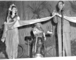 Movie star Melvin Douglas, part of USO troupe, cutting the ribbon during a USO performance at Gushkara, India, during WWII.