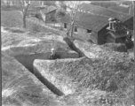 Flyer in air raid slit trench at Chanyi (Zhanyi), during WWII. Barracks behind.