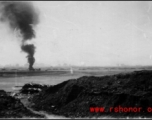 An American airplane burning in the distance after a Japanese air raid. In China, during WWII.