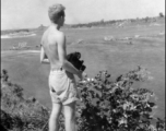 Robert Riese, camera in hand, looks over destroyed railway bridge in Liuzhou, in 1945, during WWII.