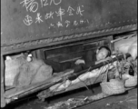 A Chinese refugee stashed away on a precious spot on a train during the evacuation in Guangxi during the fall of 1944. The writing above is a message from someone for another person to meet up on that train car.