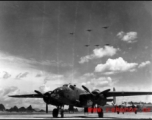 A B-25 on the ground at an American air base in Guangxi province, China, during WWII, with six B-25s flying in formation overhead.