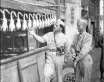 16th Combat Camera Unit photographer Selig Seidler and another man inspect ducks at a restaurant in China during WWII.