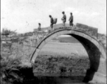 Chinese pedestrians cross arched stone bridge in SW China during WWII.