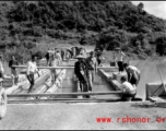 Getting a few last vehicles across a bridge at Liuzhou before the Japanese advance in the fall of 1944. The bridge decking planks have been removed, but there are enough free planks that by moving a few planks, then moving forward a bit on those planks, then moving a few more planks, the jeep can creep across.