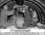 Bundles to be dropped by parachute are being tied to static line. The chutes will open automatically when kicked from the doorway to besieged Chinese troops by members of the Fourteenth Air Force Transport Unit.