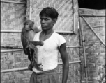 A man poses with a chained monkey in India during WWII.    From the collection of David Firman, 61st Air Service Group.