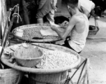 Local people selling peanuts in a market in Yunnan province, China. During WWII.