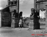 Two women walk through a ceremonial gate in Yunnan province during WWII.