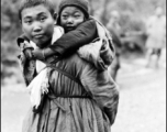 Refugee child being carried while fleeing around either Liuzhou or Guilin during the evacuation before the Japanese Ichigo advance in 1944, in Guangxi province.