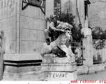 "Stewart, our unit clown" standing on a stone lion near a gate in Yunnan province, China, during WWII.