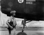 Combat Photographer Harold "Hal" Geer examines masking on bomb icons on a B-25  of the 11th Bomb Squadron (indicated by the "Mr. Jiggs" insignia) readying for painting to indicate three more bombing missions. In southwest China during WWII, as photographed by Selig Seidler, 16th Combat Camera Unit, in the CBI during WWII.