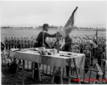 Chinese soldiers in ranks observe ceremonial hand off of banner or flag.