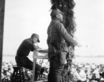 Chinese offiGen. Wei Lihuang (卫立煌) gives speech to assembled troops, and another person makes notations on a paper, on stage during rally.er gives speech during exercises in southern China, probably Yunnan province, or possibly in Burma.