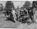 To get a great photo, a GI lends a hand to Indian work crew to pull concrete roller.  Scenes in India witnessed by American GIs during WWII. For many Americans of that era, with their limited experience traveling, the everyday sights and sounds overseas were new, intriguing, and photo worthy.